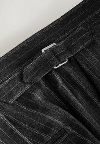 Gray wool trousers with vertical pinstripes, featuring a flat waistband, buckle closure, and textured fabric. Accentuated by subtle details.