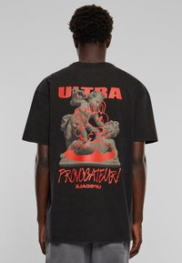 Černé bavlněné tričko s velkým červeným grafickým potiskem zobrazujícím sochu a textem "ULTRA" a "PROVOCATEUR!" v tučném písmu.