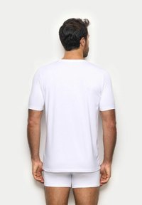 T-shirt bianco a maniche corte realizzato in un tessuto morbido, con scollatura rotonda classica e una vestibilità rilassata. Indossato con boxer bianchi abbinati.