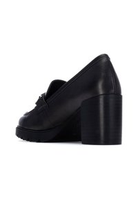 Zapato de tacón alto de cuero negro con tacón grueso, punta afilada y herrajes decorativos en el empeine. Suela texturizada para mayor tracción.