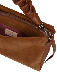 Bruine leren handtas met een suède buitenkant, gevlochten handvat en ritssluiting. Het interieur heeft een kastanjebruine voering en een merkembleem.