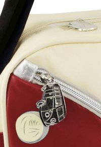 Rote und cremefarbene Tasche mit einem silbernen Reißverschluss und einem Metallanhänger in Form eines Vintage-Vans. Glatte Textur mit glänzender Oberfläche.