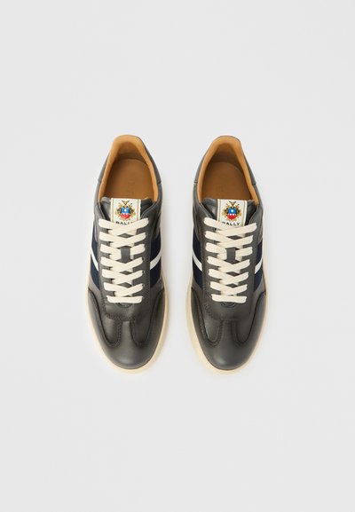 Γκρι δερμάτινα αθλητικά παπούτσια με ναυτικό μπλε ρίγες, κρεμ κορδόνια και ετικέτα με λογότυπο. Διαθέτουν λείο εξωτερικό, στρογγυλή μύτη και υφασμένη σόλα.