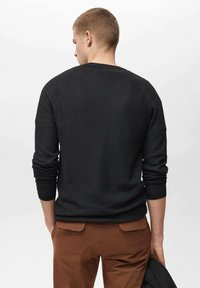 Črn pleteni pulover z raglan rokavi, ki ima teksturiran vzorec. Zadnji del je telesu prilegajoč z okroglo izrezom.