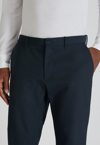 Navyblaue, maßgeschneiderte Hose aus glattem Stoff, mit Knopfverschluss, seitlichen Taschen und schlanker Passform. Geeignet für sowohl legere als auch formelle Anlässe.