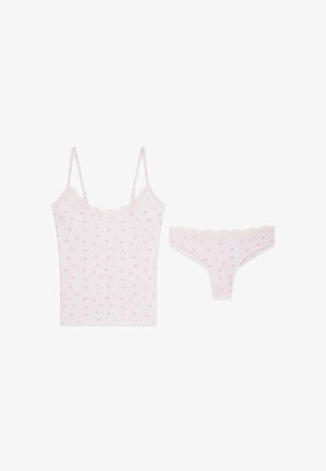 Weißes Damen-Camisole und passender String mit pinkfarbenen Herzmustern und Spitzenbesatz auf weißem Hintergrund.