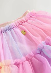 Jupe en tulle superposée rose et violette avec une ceinture élastique scintillante et un petit charme rond en or attaché au tissu.
