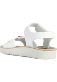 Sandalia de plataforma blanca con plantilla de corcho acolchada, diseño abierto con correas y suela texturizada, que ofrece un estilo fácil de poner y quitar.