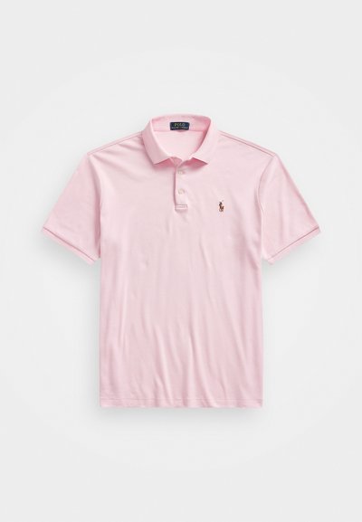 Svetlo roza polo majica iz bombaža. Kratki rokavi, ovratnik s tri gumbe in majhna vezenina na prsih.