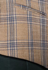 Kratkowana marynarka w kolorze brązowym, z niebieskimi i beżowymi wzorami, wykonana z teksturowanej tkaniny, z jedną kieszenią na piersi i ciemnozielonym wykończeniem.