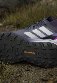 Scarpa sportiva viola scuro con strisce bianche. Dotata di suola in gomma nera texturizzata, pattern di battistrada pronunciato e logo "Continental".