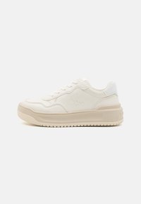Sneaker bianco in pelle con un design testurizzato, suola spessa e logo impresso. Presenta una chiusura con lacci e un colletto imbottito. Accenti di colore tenui.