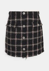 Minijupe en tweed à carreaux noir et blanc avec ourlet effiloché, dotée de deux poches avant et de détails à boutons argentés.