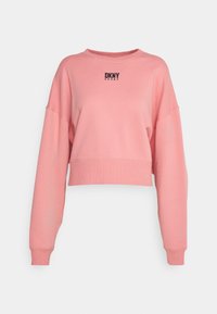 Sweatshirt rose court avec des manches longues, des poignets côtelés, et un logo noir "DKNY SPORT" sur la poitrine. Texture douce, semblable au coton.