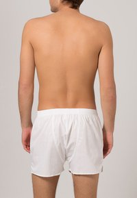 Boxer shorts bianchi in cotone con una cintura elastica, caratterizzati da una texture liscia e un design semplice, visti da dietro.