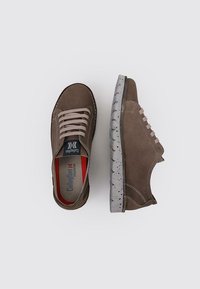 Zapatos de ante marrón con cordones beige, que presentan una suela gris texturizada y un revestimiento interior rojo. Las costuras laterales añaden detalle.