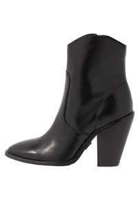 Botín de cuero negro a la altura del tobillo con punta afilada, tacón bloque de altura media y textura suave. Presenta un detalle de costura en el costado.