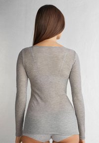 Šedý dlouhý rukáv top z ribbed materiálu, s mírným výstřihem a přiléhavým střihem, v kombinaci se šedými šortkami, na neutrálním pozadí.