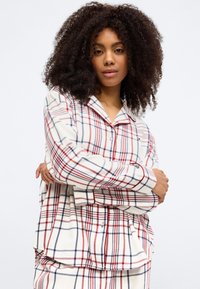 Conjunto de pijama de franela de manga larga en blanco, rojo y azul marino. Incluye una camisa abotonada con bolsillos y un ajuste relajado. Textura de tela suave.