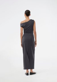 Pelēks vienvirziena maxi kleita, izgatavota no mīksta auduma, ar pieguļošu siluetu, aizmugures šķirto un īsām piedurknēm. Minimālistisks dizains bez rakstiem.