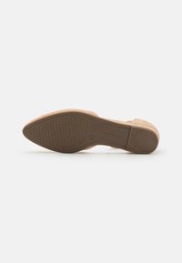 Semelle de chaussure à talon haut beige avec une texture en caoutchouc antidérapant, présentant un bout arrondi et une finition lisse, étiquetée avec le nom de la marque et la taille.
