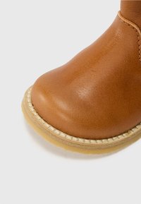 Brune lærstøvel med avrundet tå, strukturert overflate, kontrasterende beige søm og gummistøvel for godt grep.