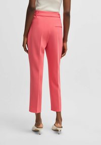 Roze, op maat gemaakte broeken met een slim fit, voorzien van zijzakken, een gladde textuur en een taille detail. Gecombineerd met crèmekleurige heeled mules.