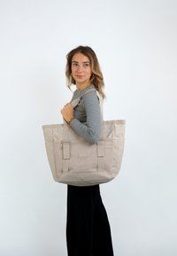 Beige vászontáska, tartós anyagból, geometrikus mintázattal, masszív fogantyúkkal és nagy tárolórekesszel.
