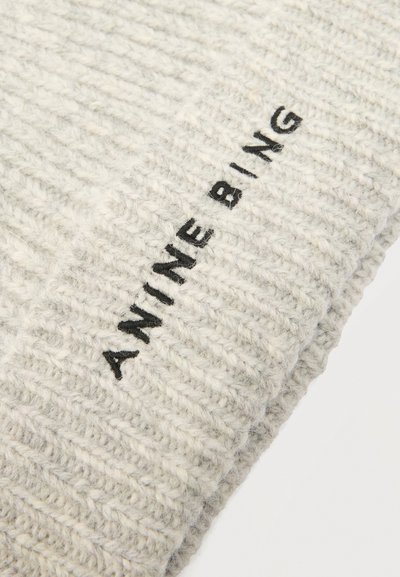 Világosszürke bordázott kötött anyag fekete hímzett "ANINE BING" felirattal, amely egy behajtott szélén látható.