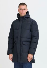 Marineblå dunjakke med hette, som har glidelås foran, to lommer foran, quiltet design og myk tekstur.