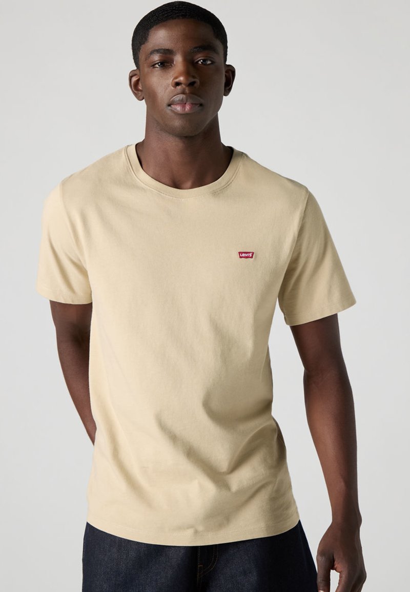 Beige cotton t-shirt with a crew neck, short sleeves, and a small red Levi's logo on the chest. Casual fit, smooth texture.