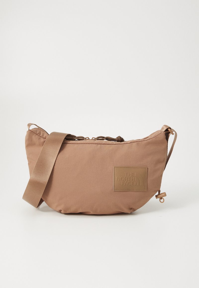 Bolso de hombro de nylon marrón con superficie texturizada, correa ajustable y un logotipo rectangular en relieve en la parte frontal. Forma redondeada con cremallera.