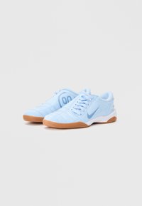 Sapatilhas atléticas azul claro com um superior texturizado, sistema de atacadores e sola de borracha natural. Apresenta um swoosh da Nike e um padrão cosido na biqueira.