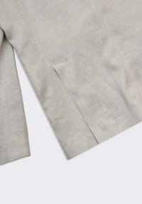 Ljusgrå linneblazer med en enkel sidficka och slät textur, med en skräddarsydd design och rena linjer.