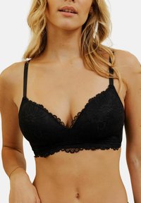 Bralette en dentelle noire avec une forme triangulaire, un motif floral, des bords en dentelle et des bretelles ajustables, fabriquée dans un tissu doux et texturé.
