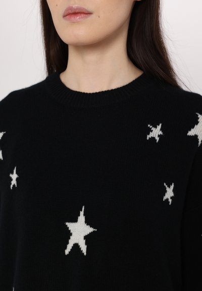 Black knit sweater with a round neckline, featuring white star patterns scattered across the fabric. Soft texture, casual design.