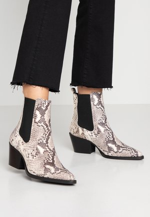 Botines con estampado de piel de serpiente, con puntera afilada, paneles laterales elásticos negros y un tacón mediano de bloque. Forrados con una textura suave.