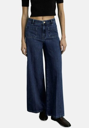 Wide-leg jeans in dark blue denim, featuring two front pockets, a high waist, and a loose fit. Textured fabric with visible stitching.
