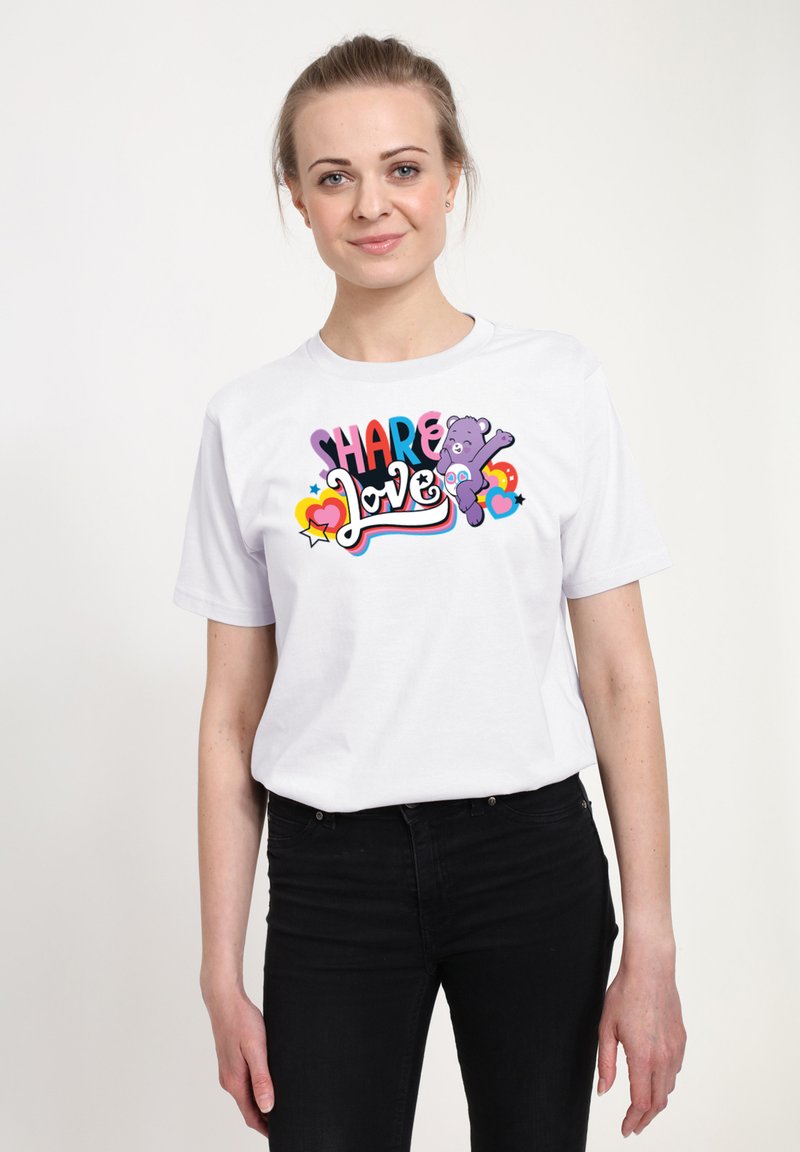 Vit bomull t-shirt med en färgglad grafik som säger "DELA Kärlek" med en tecknad björn och hjärtan som dekorationer. Kortärmad, rundad hals.
