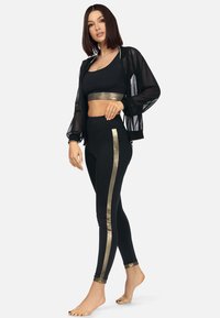 Czarny zestaw odzieży sportowej z krótką bluzą i przezroczystą czarną kurtką; posiada złote boczne paski na legginsach; gładka tekstura, dopasowany krój.