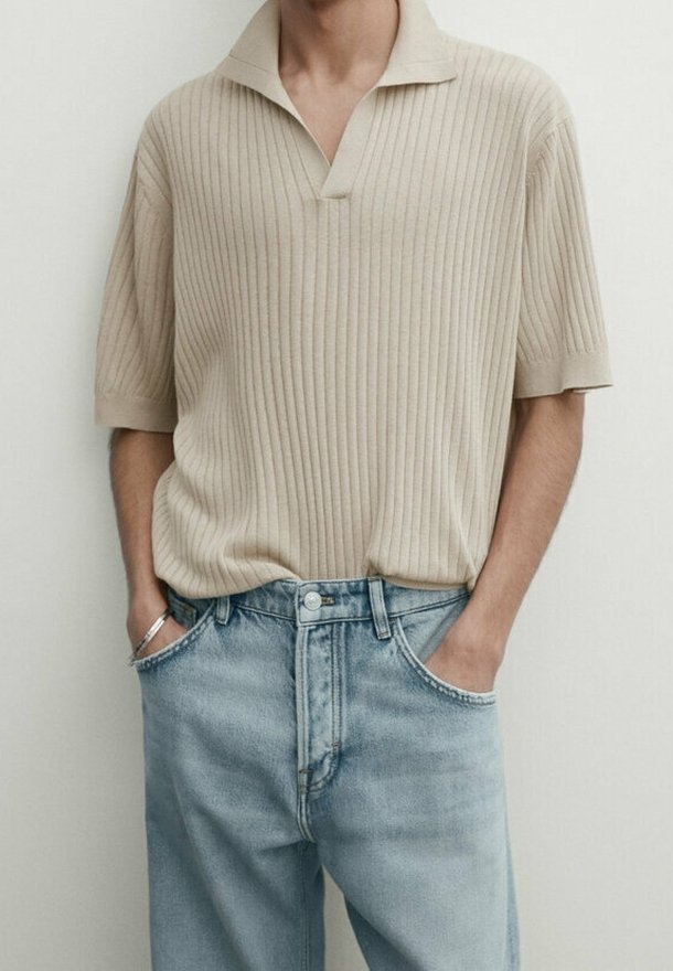 Beige ribbattu polo-paita kauluksella, yhdistettynä vaaleansinisiin farkkuihin. Paidassa on lyhyet hihat ja rento istuvuus.