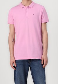 Polo shirt en coton rose avec un col classique, une patte de boutonnage à deux boutons, des manches courtes et un petit logo de marque sur la poitrine.