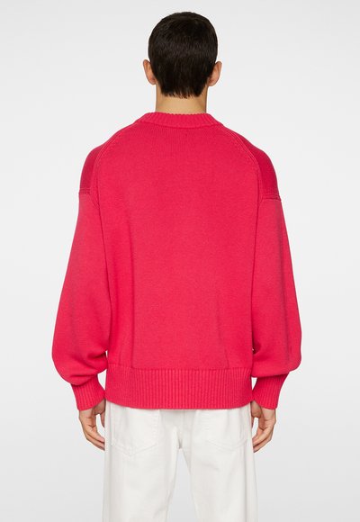 Overdimensioneret, lys pink sweater med ribstrikket kant og manchetter, brede ærmer og rund halsudskæring. Glat strikstruktur, minimalistisk design.