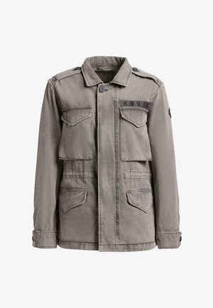 Pelēka militārā stila jaka ar pogām, četrām pārsegu kabatām un "K.H.U.J.O" uzplečņu uzlīmi kreisajā krūtīs.