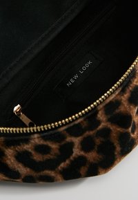 Bustina con stampa leopardata e interno nero, dotata di chiusura a zip con cerniera color oro. Etichetta con la scritta "NEW LOOK." Texture morbida.