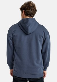 Navy blue hoodie made of soft fabric, featuring a large hood and ribbed cuffs. The back shows a relaxed fit with a smooth texture.