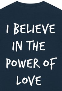 T-shirt en coton bleu marine avec un texte blanc bien visible qui indique « JE CROIS EN LA PUISSANCE DE L'AMOUR » dans une police manuscrite en gras.