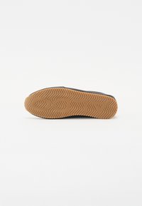 Mustad must-saapad tekstureeritud kummist taldaga, millel on zic-zac muster ja toorkummi värvi väljtald. Minimalistlik disain, kus ei ole nähtavat brändingut.