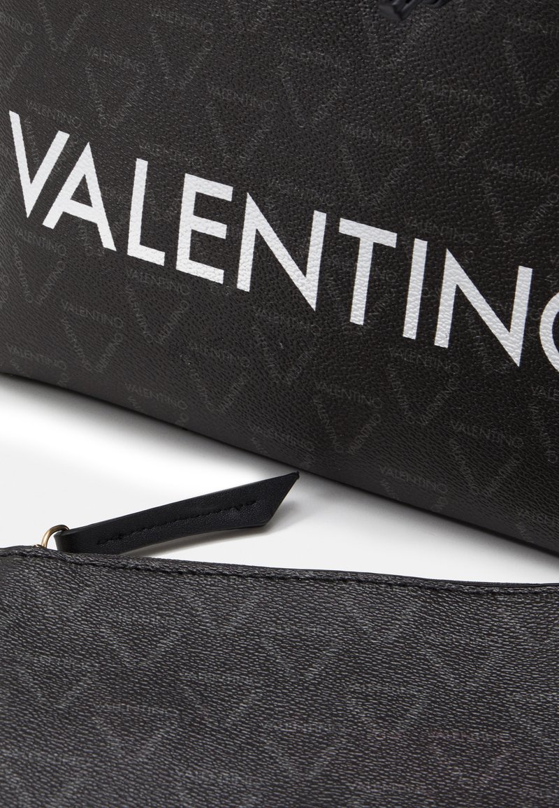 Zwart, gestructureerd leren accessoire met een herhalend logopatroon, met op de voorkant de gedurfde witte letters "VALENTINO".