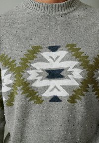 Maglione a maglia realizzato con filato grigio, caratterizzato da un motivo tribale in verde oliva, bianco e blu navy. Scollo rotondo con bordo a coste.